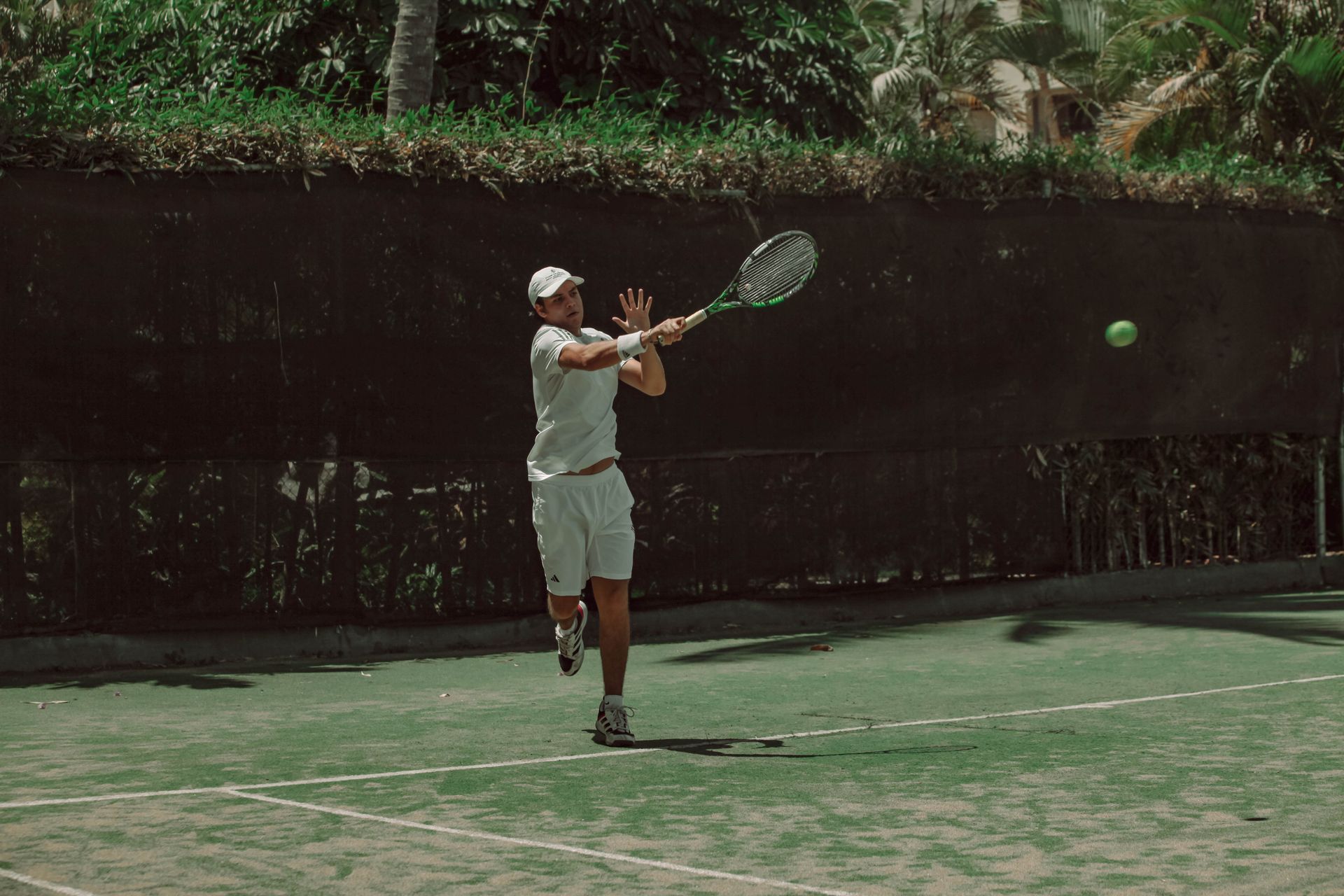 Player sliding into a shot on an astro turf tennis court