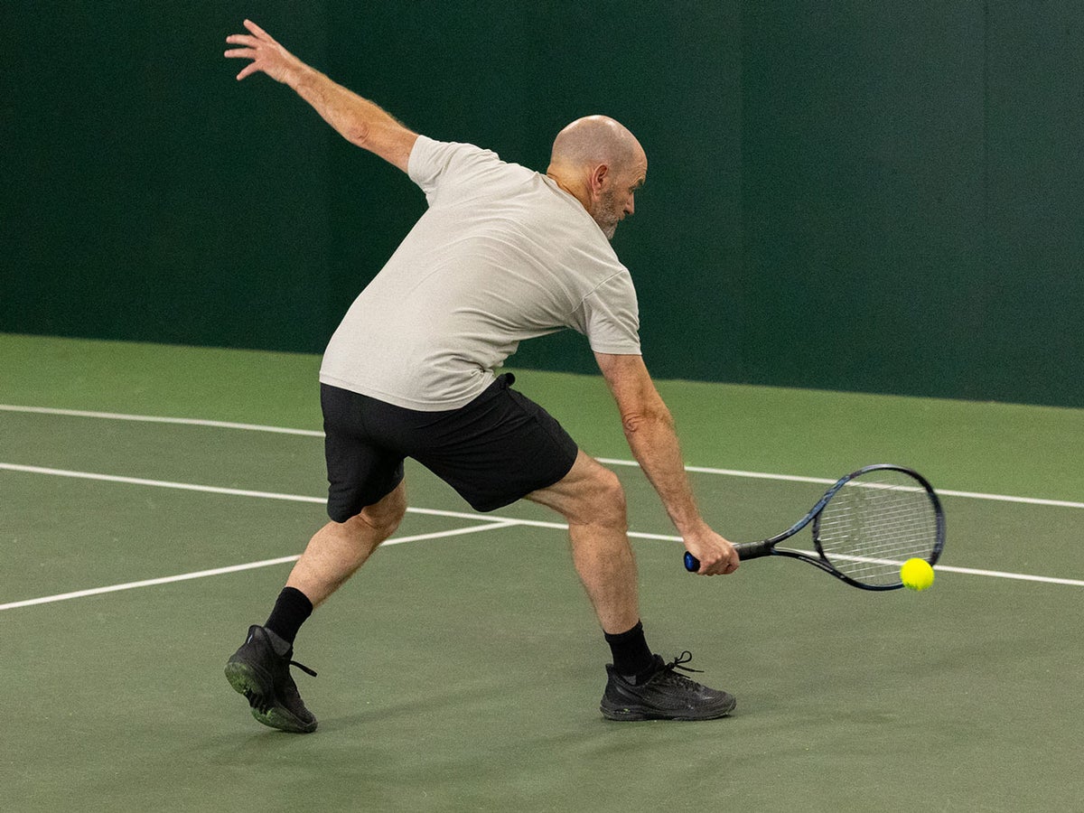 Player moving fast across an astro turf court in lightweight tennis shoes