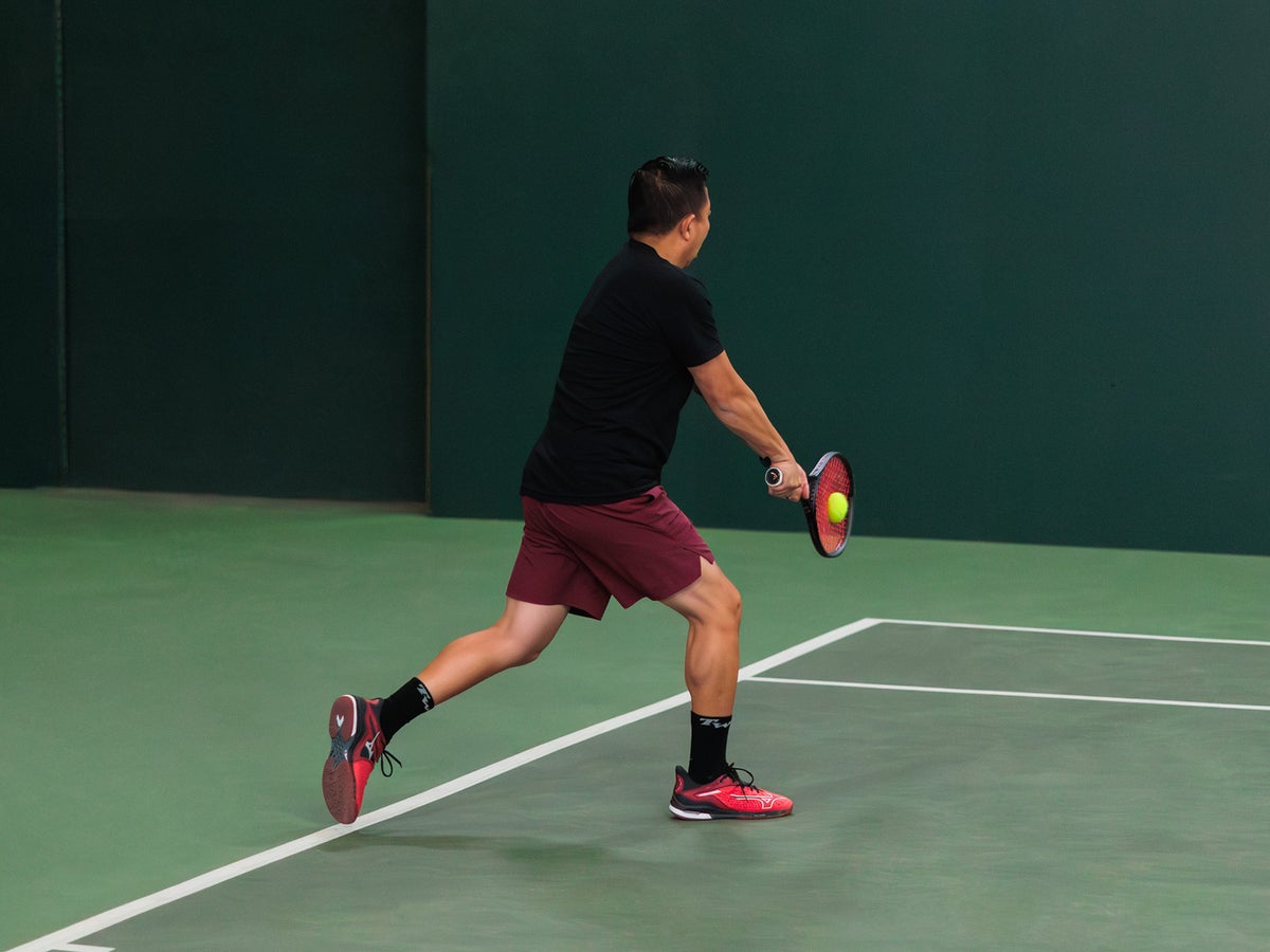 Player sprinting for a wide ball on an astro turf court