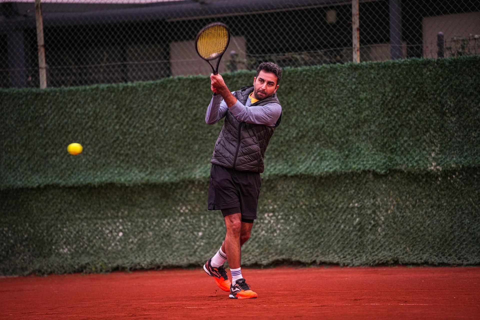 Player in full stretch for a low forehand on a hard court