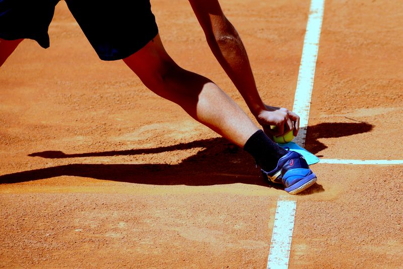 Tennis player cutting hard laterally on a clay court