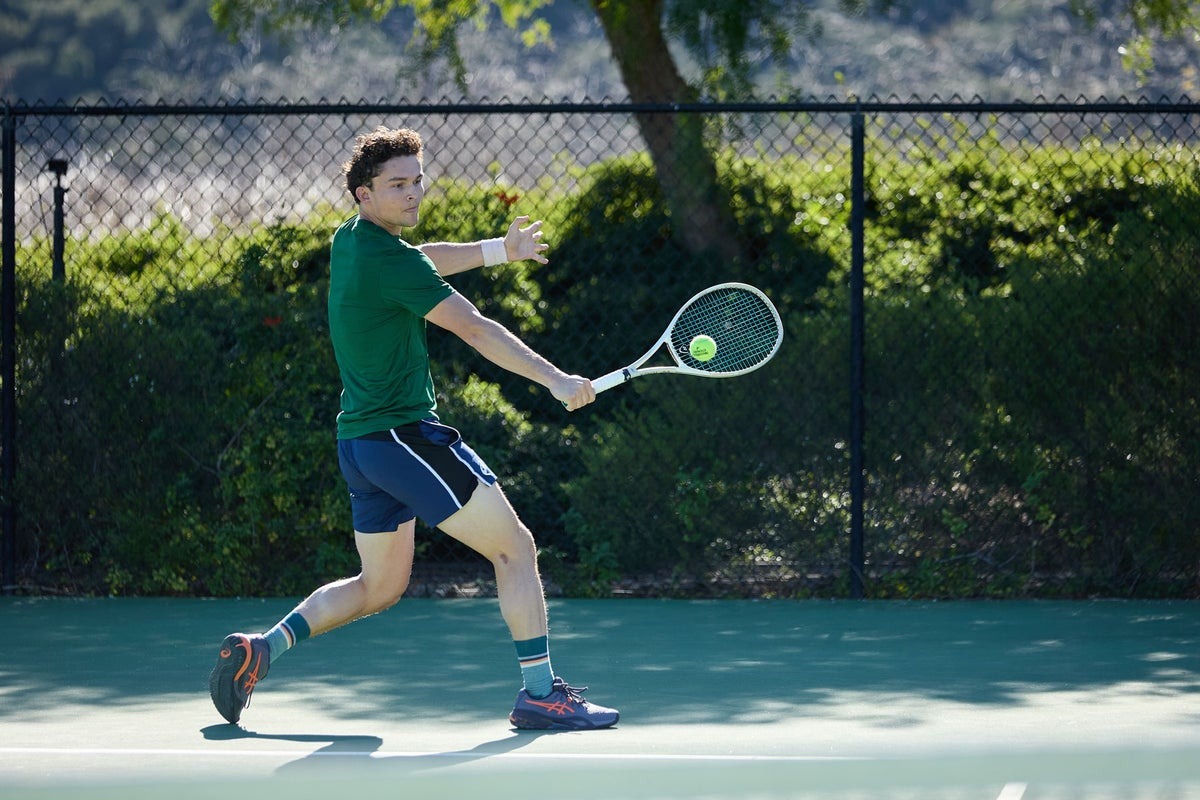 Player bracing through a hard lateral stop in structured tennis shoes