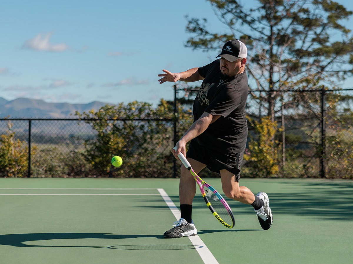 Player hitting a forehand in adidas Barricade shoes on an outdoor hard court