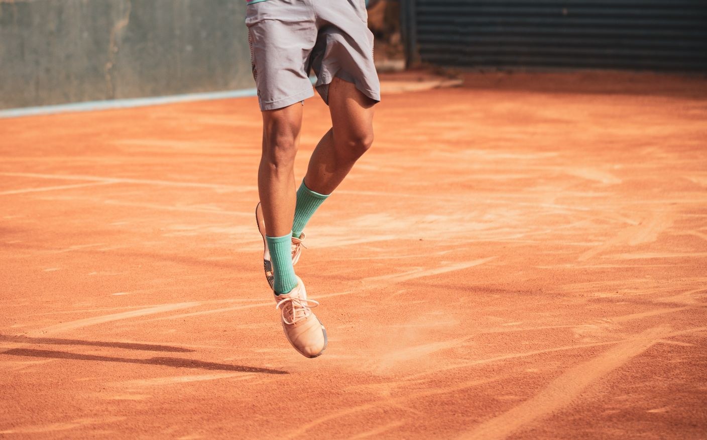 Airborne legs in light court shoes during a backhand on clay